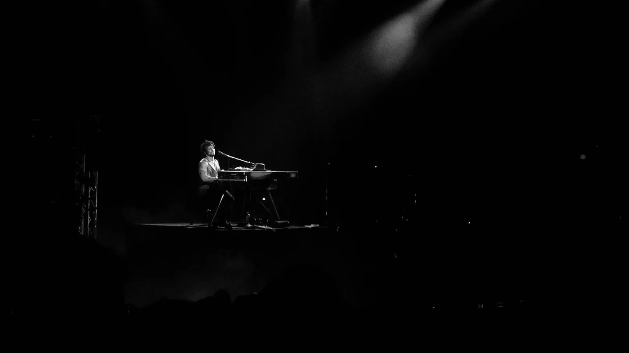 D’Angelo sits at a Rhodes keyboard under a spotlight during his 2012 Brixton Academy concert.