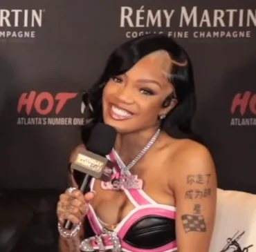 GloRilla smiling during a HOTSPOTATL YouTube interview, holding a microphone.