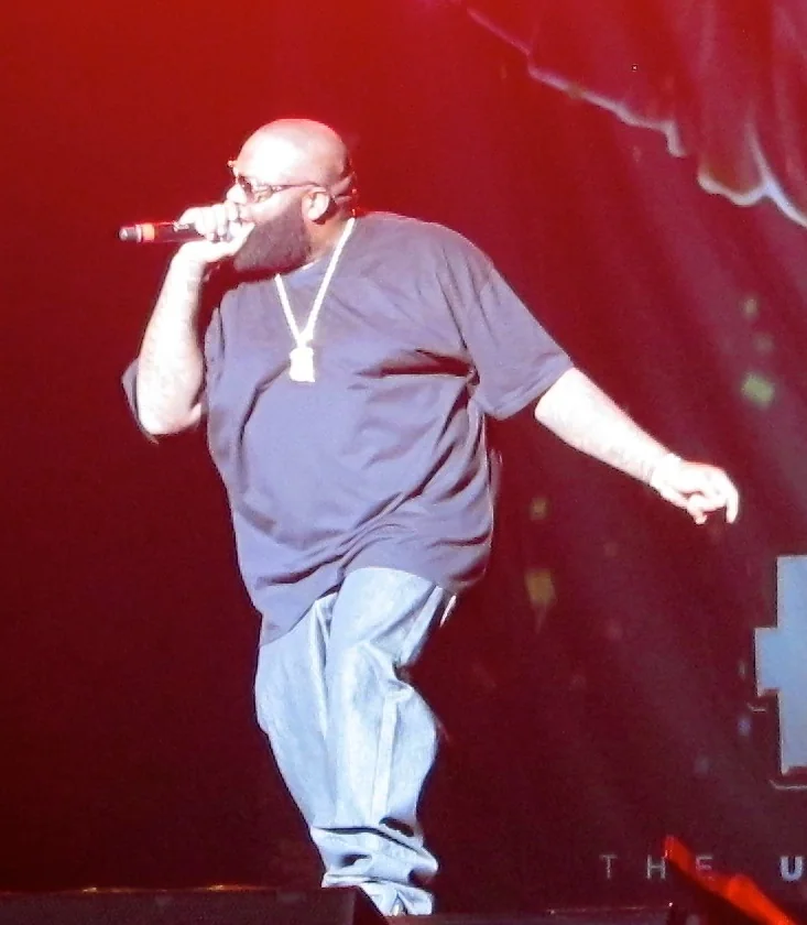 Rick Ross performs into a microphone in sunglasses at a 2011 concert.